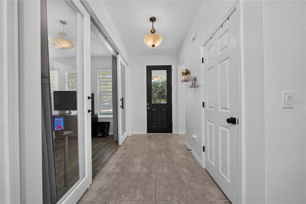 A tiled entryway features a black front door, white interior doors, and glass sliding doors — 16273 TALIESIN STREET, WINTER GARDEN, FL