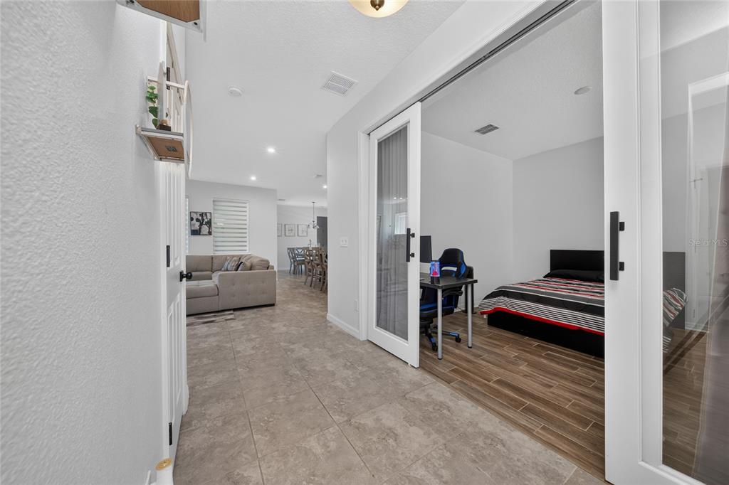 A tiled hallway leads to a living area and a bedroom with glass French doors — 16273 TALIESIN STREET, WINTER GARDEN, FL
