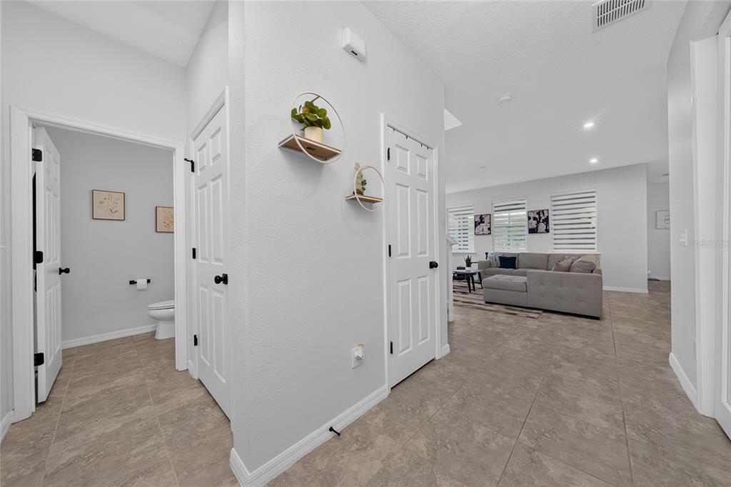 A hallway with tile flooring leads to a bathroom and an open-concept living room — 16273 TALIESIN STREET, WINTER GARDEN, FL