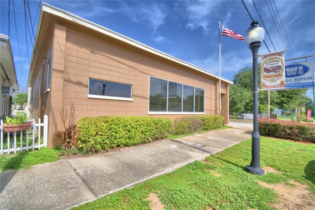 A tan, single-story commercial building with a sidewalk, landscaping, and a street lamp — 221 N SCENIC HIGHWAY, FROSTPROOF, FL