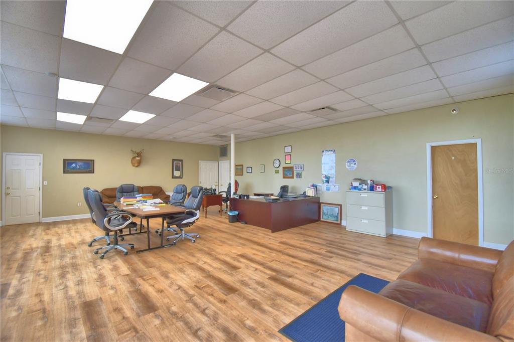 An office space features wood-look flooring, a drop ceiling, a conference table, and a desk — 221 N SCENIC HIGHWAY, FROSTPROOF, FL