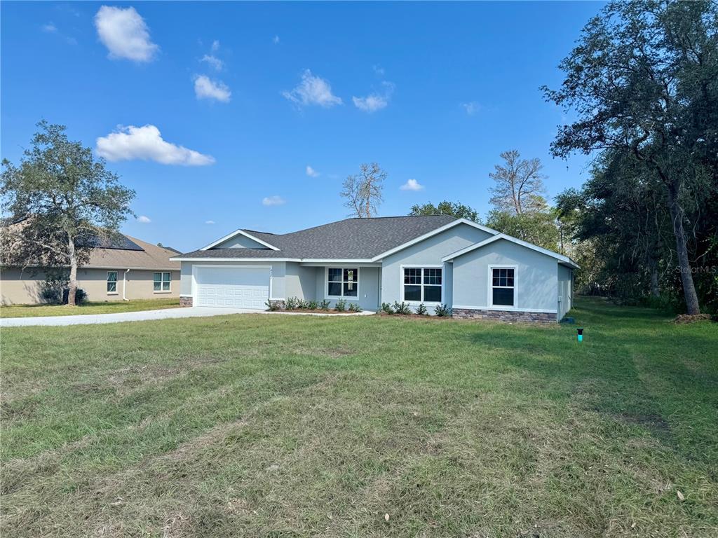 A single-story house with a light gray exterior, stone accents, and a two-car garage — 5513 SW 137TH COURT, OCALA, FL