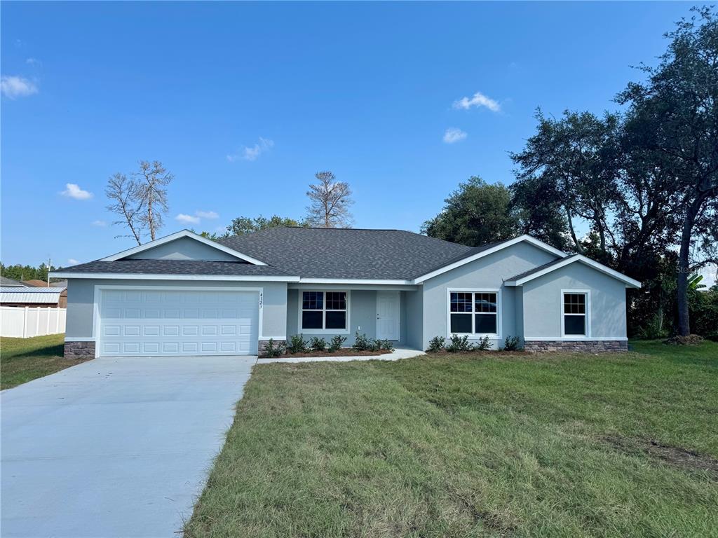 A single-story house with a gray exterior, white garage door, and a dark shingled roof — 5513 SW 137TH COURT, OCALA, FL