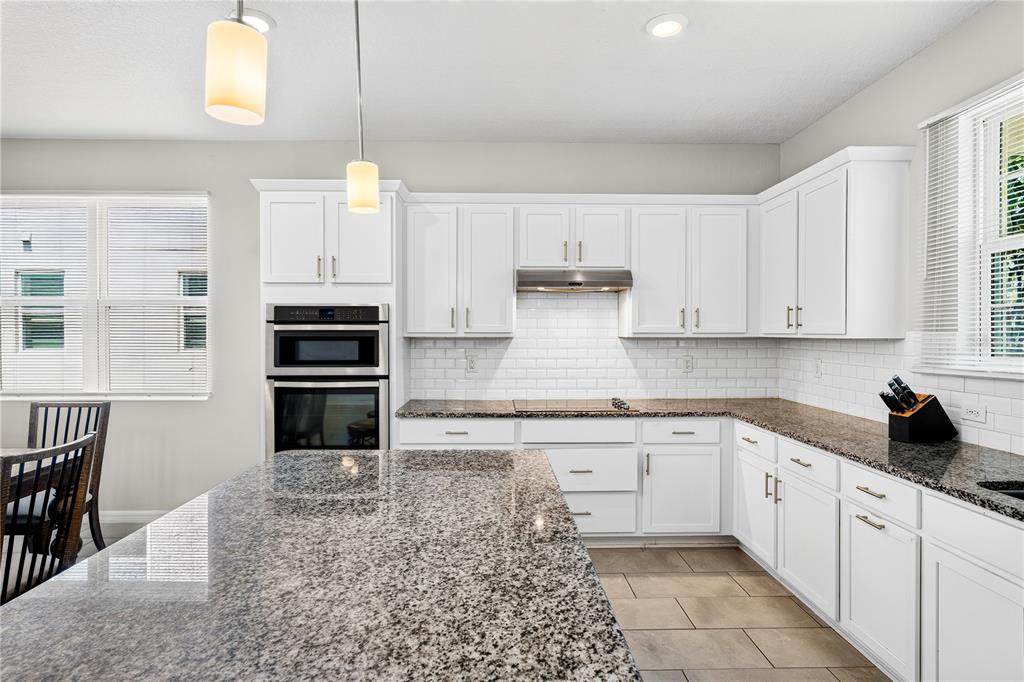 A kitchen with white cabinets, granite countertops, stainless steel appliances, and a large island — 13831 FARELLA ALLEY, WINDERMERE, FL
