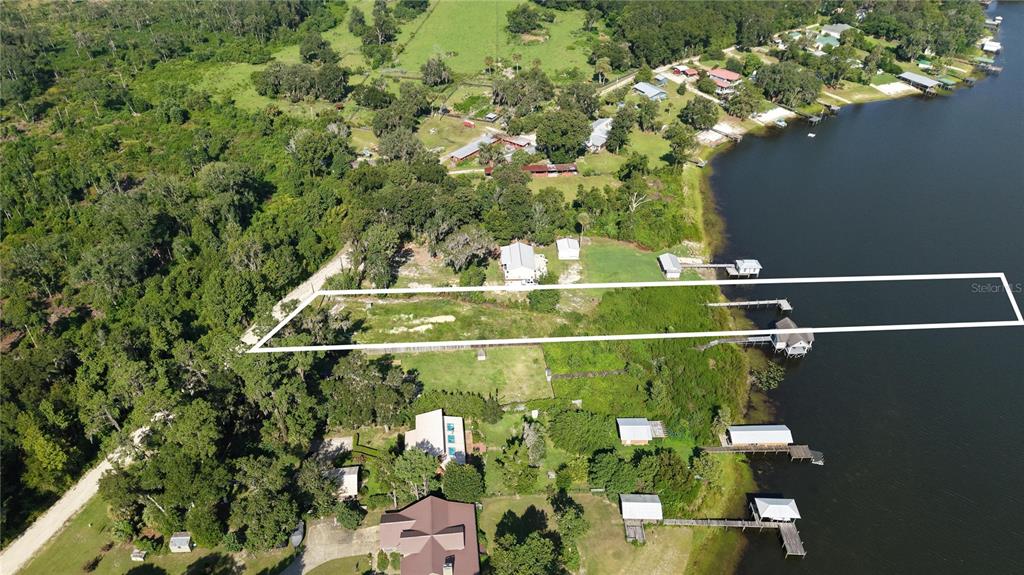 An aerial view shows a rectangular property outline extending from a wooded area to a lake — 201 FLORADANDY ROAD, HAWTHORNE, FL