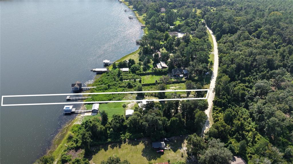An aerial view shows a rectangular property outline extending from a dirt road to a lake — 201 FLORADANDY ROAD, HAWTHORNE, FL