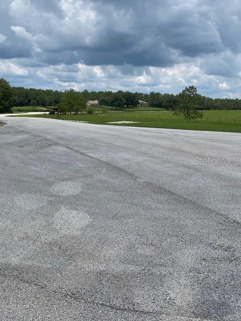 A paved road borders a large, grassy vacant lot with a utility post — 5698 QUICKSILVER, FLORAL CITY, FL
