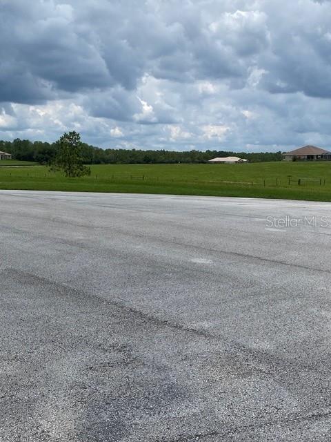 A paved road leads toward a grassy field with trees and a distant house — 5698 QUICKSILVER, FLORAL CITY, FL