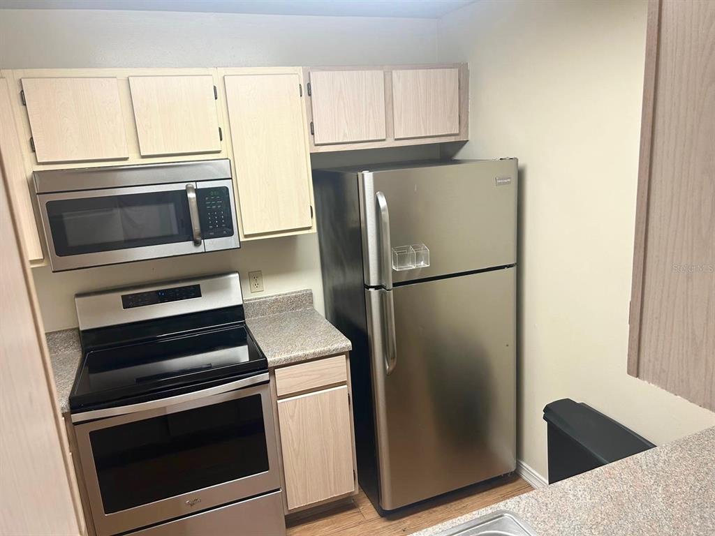 A kitchen features light wood cabinets, stainless steel appliances, and speckled laminate countertops — 2360 SW ARCHER ROAD UNIT 915, GAINESVILLE, FL