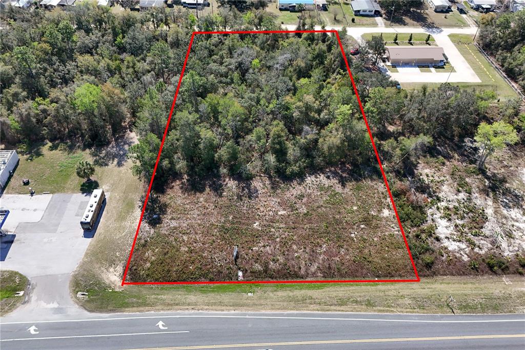 An aerial view shows a rectangular, partially wooded vacant lot outlined in red along a road — 18000 E HWY 40, SILVER SPRINGS, FL