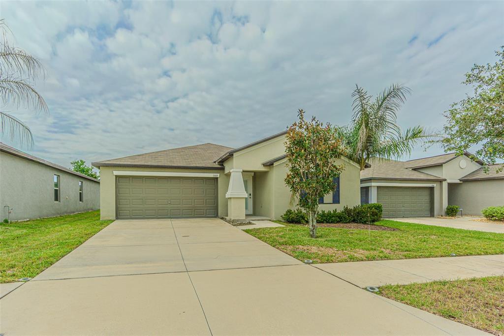 A single-story suburban house with a concrete driveway, two-car garage, and a small front yard — 13009 MAJESTIC GARDEN LANE, RIVERVIEW, FL