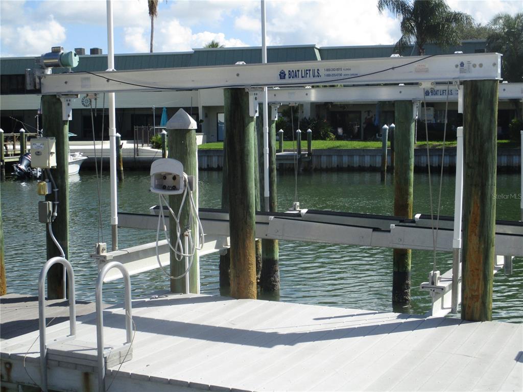A boat lift with a metal frame is installed over a canal at a dock — 11855 1ST STREET E, TREASURE ISLAND, FL