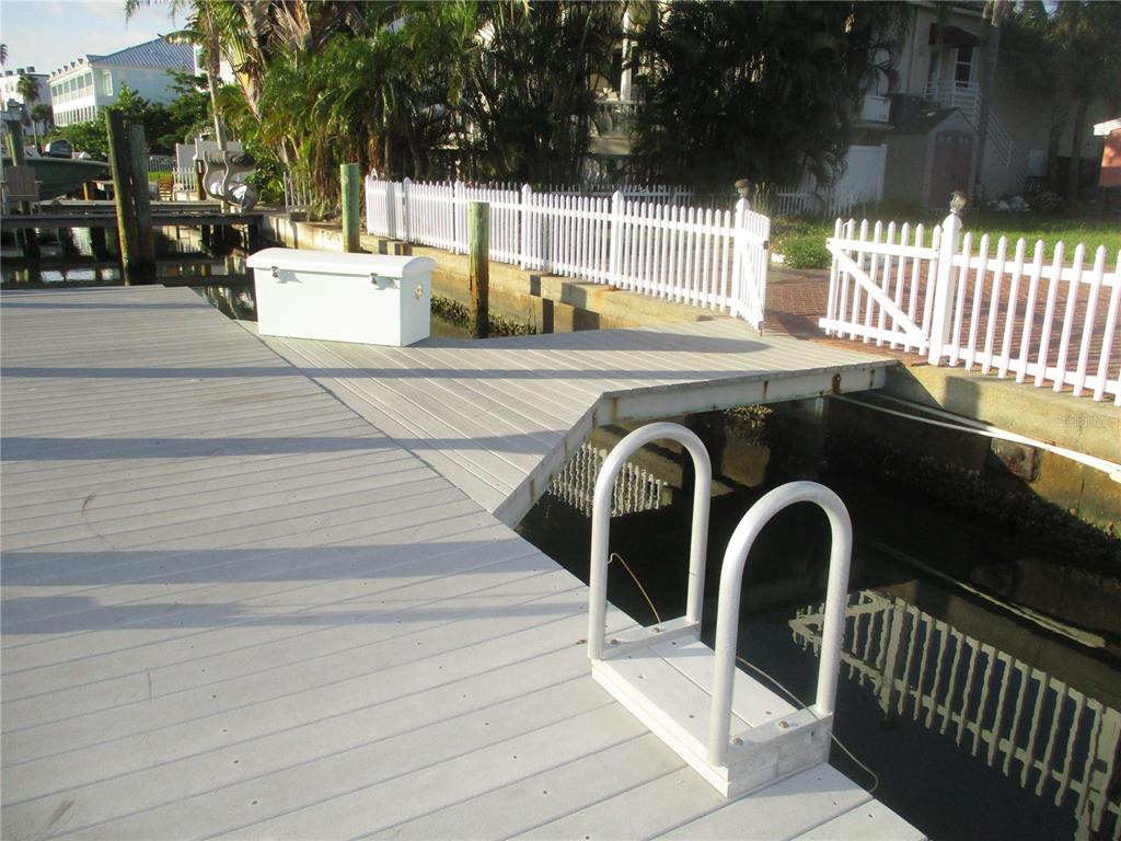 A wooden dock features a white storage chest, a metal ladder, and a white fence — 11855 1ST STREET E, TREASURE ISLAND, FL