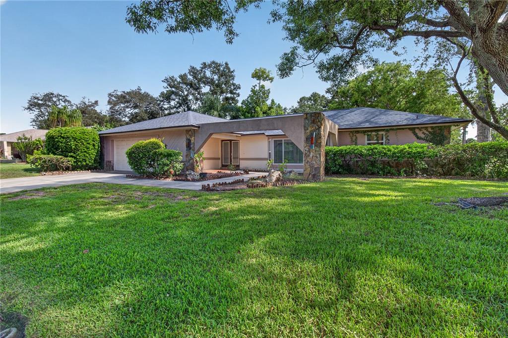 A single-story house with a large lawn, a stone-accented entryway, and a paved driveway — 10 LINDEN LANE, PALM HARBOR, FL