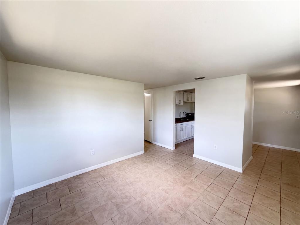An interior view shows a tiled room with light walls leading to a kitchen area — 2213 BOUYER STREET, LAKE WALES, FL