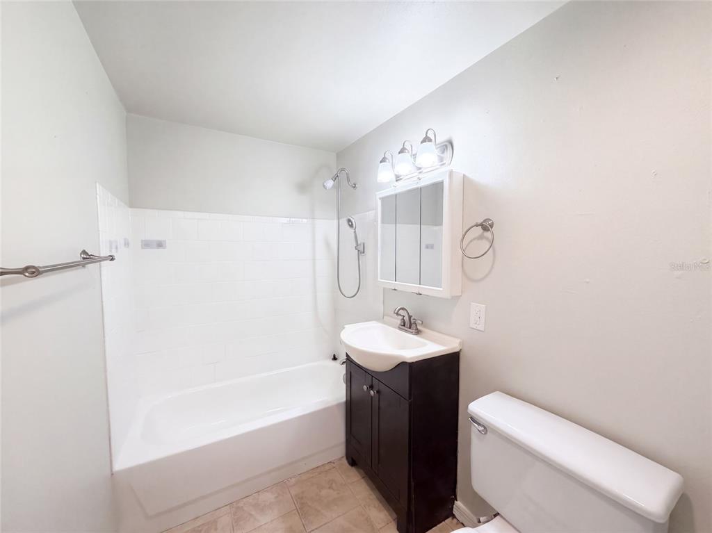 A bathroom features a white tub-shower combination, a dark vanity, and a mirrored medicine cabinet — 2213 BOUYER STREET, LAKE WALES, FL