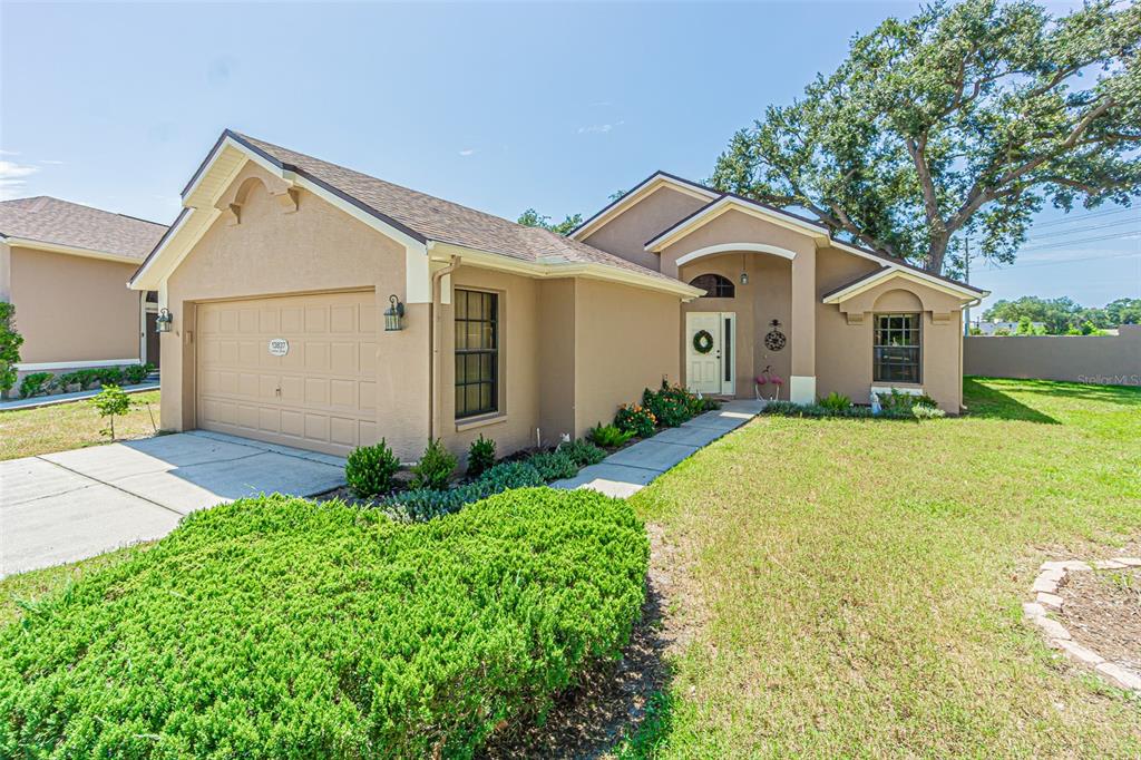 A tan single-story house with a two-car garage, arched entryway, and a large front lawn — 13837 LEROUX DRIVE, HUDSON, FL