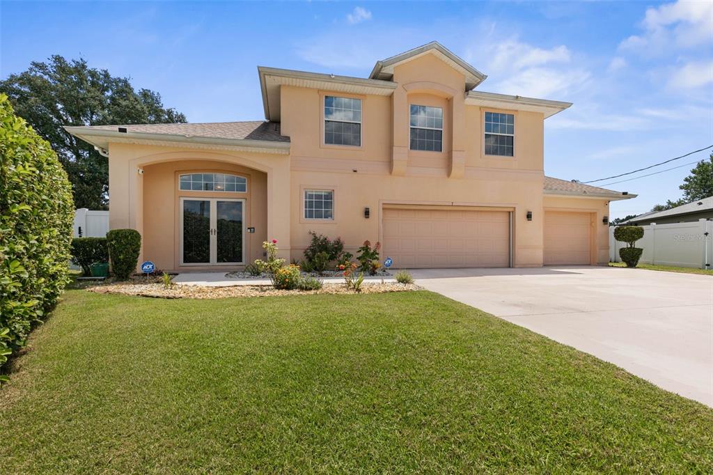 A two-story, peach-colored suburban house features a three-car garage and a front lawn — 7 FLINT PLACE, PALM COAST, FL