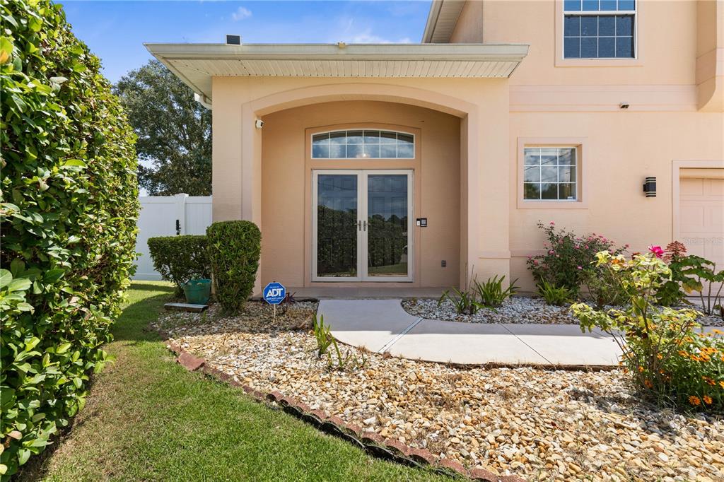 The exterior of a beige house features a covered entryway with double glass doors — 7 FLINT PLACE, PALM COAST, FL