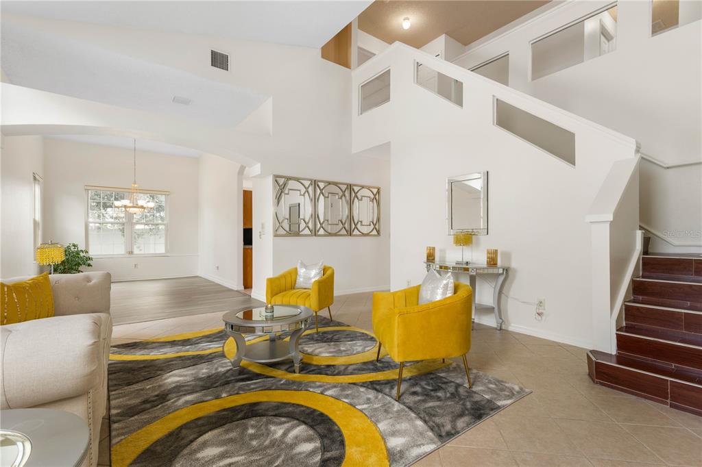 A living room features a yellow rug, two yellow armchairs, and a staircase with wood steps — 7 FLINT PLACE, PALM COAST, FL