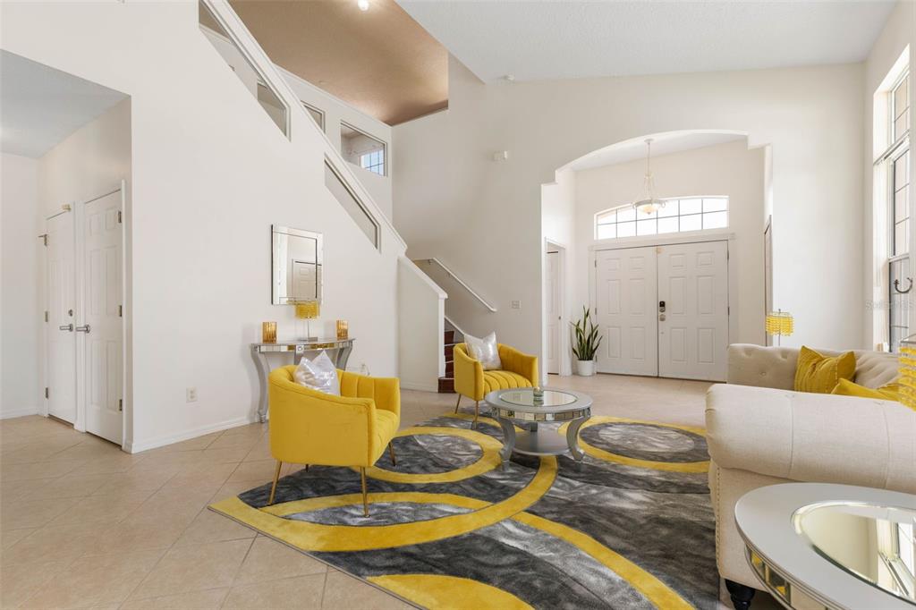 A bright living room features a yellow armchair, a patterned rug, and a high ceiling — 7 FLINT PLACE, PALM COAST, FL