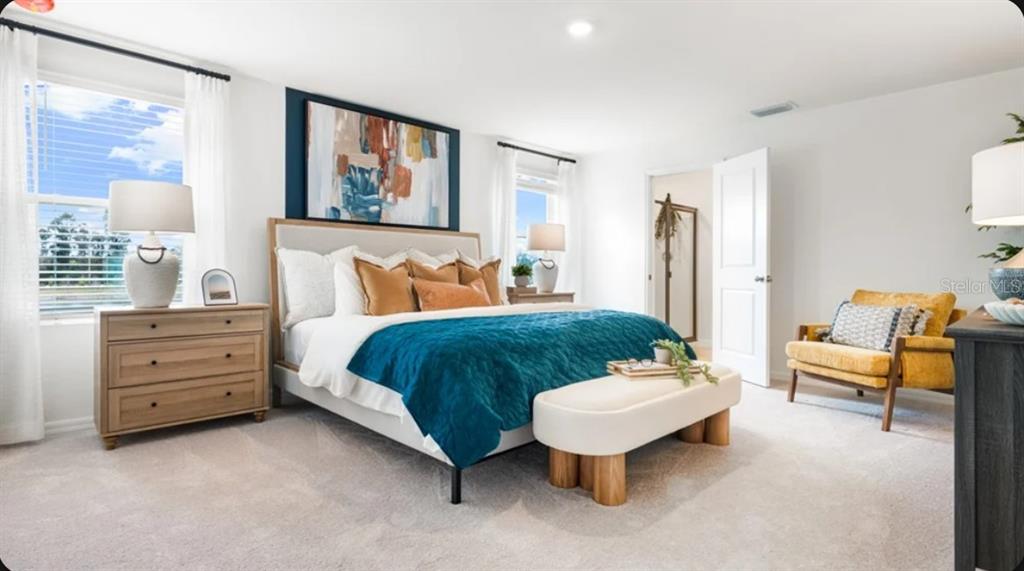 A bedroom features a bed with a teal throw, a wooden dresser, and a yellow chair — 5327 LOGGIA LANE, KISSIMMEE, FL