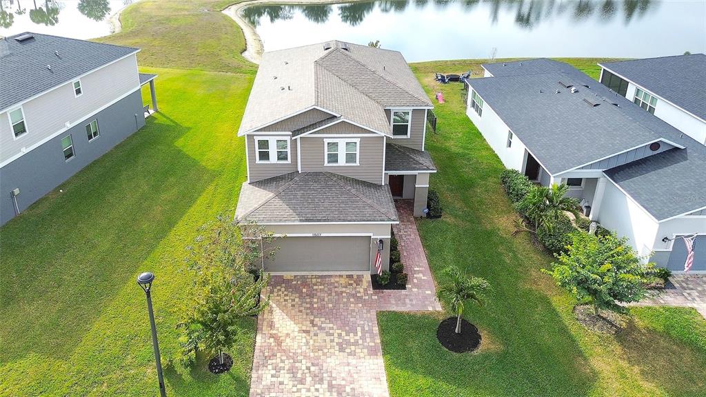 An aerial view shows a two-story suburban house with a paved driveway and backyard pond — 11507 GALLATIN TRAIL, PARRISH, FL