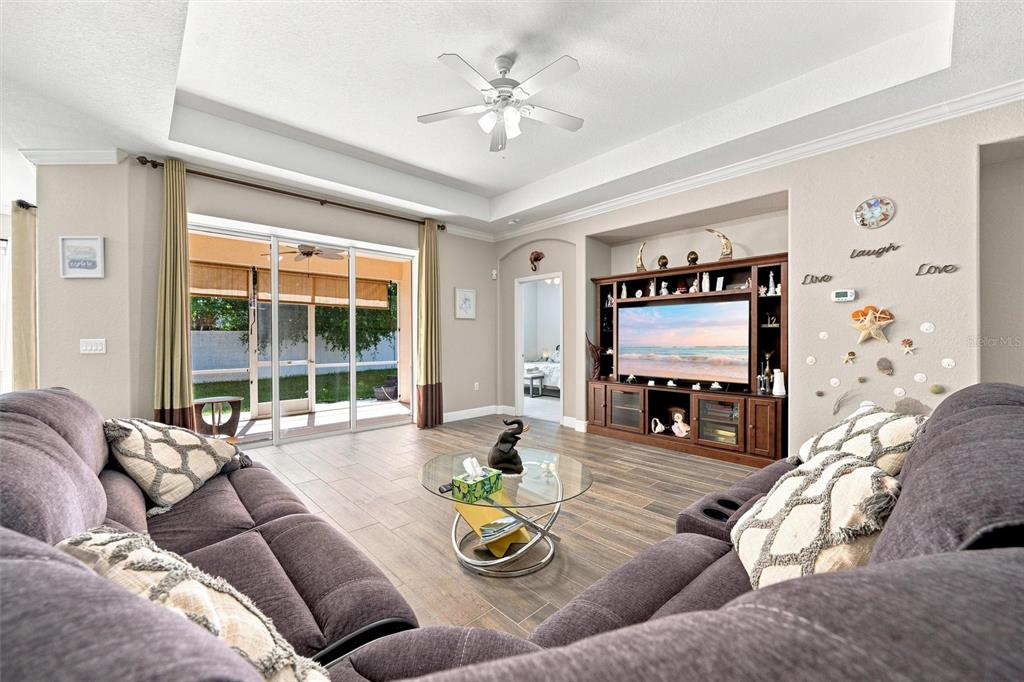 A living room features a large sectional sofa, a glass coffee table, and an entertainment center — 7707 33RD STREET E, SARASOTA, FL