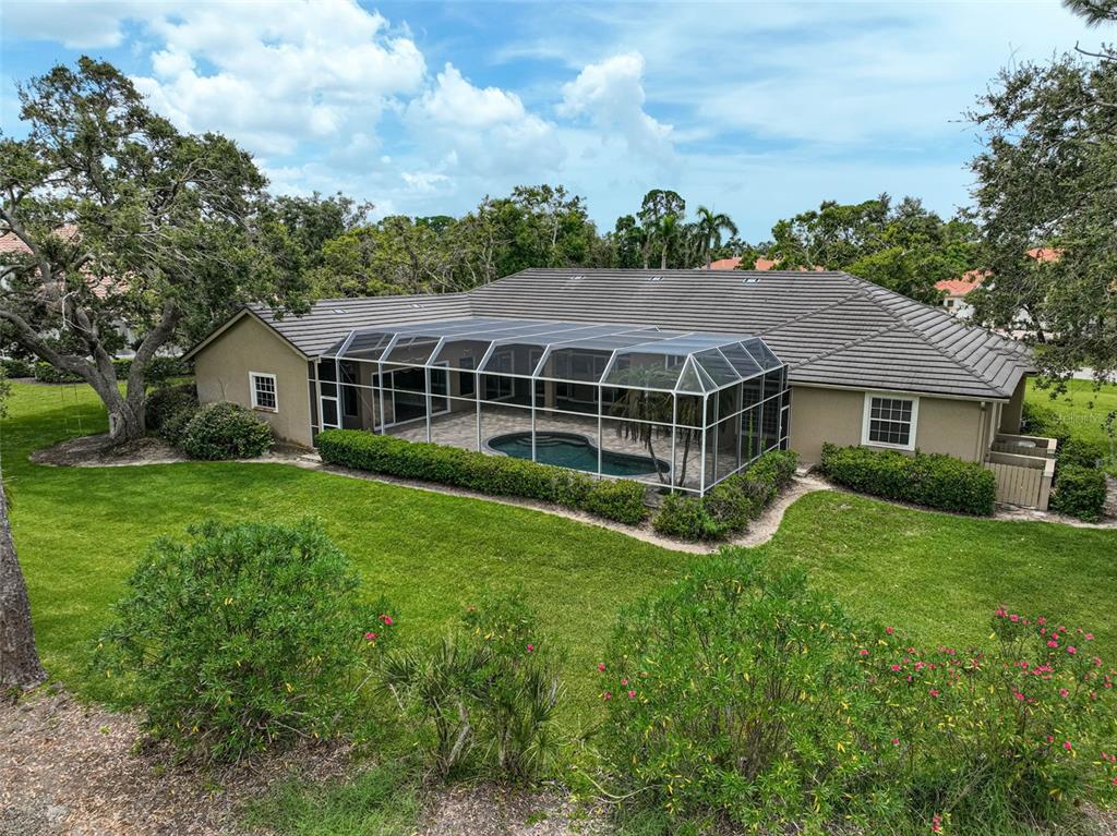 An aerial view of a house with a screened-in pool and a large grassy backyard — 852 MACEWEN DRIVE, OSPREY, FL