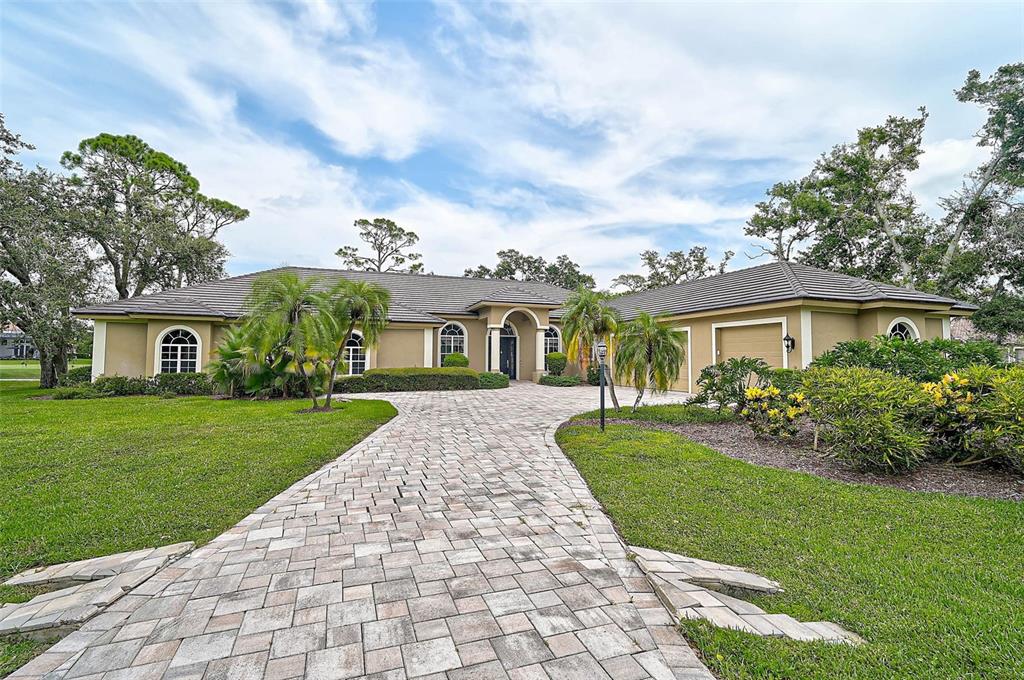 A single-story house with a paved driveway, arched windows, and a tiled roof — 852 MACEWEN DRIVE, OSPREY, FL