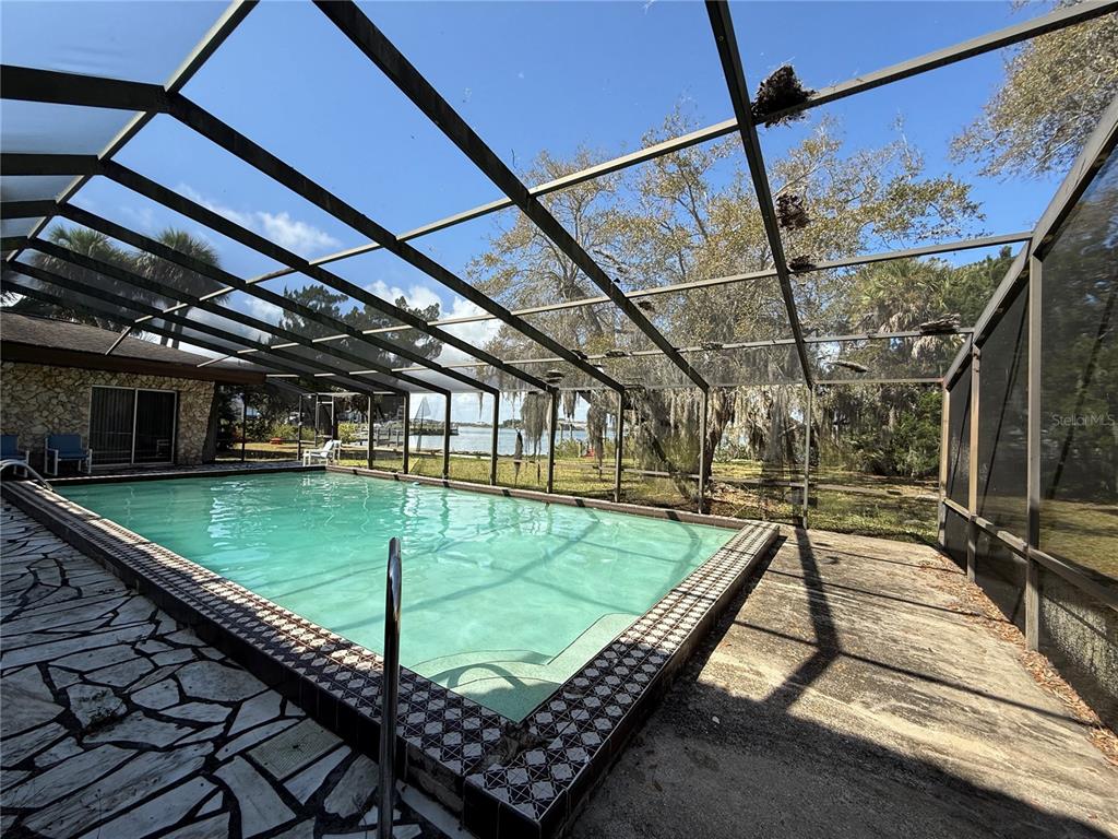 A swimming pool sits inside a screened-in enclosure with a view of a nearby waterway — 508 S INDIAN RIVER ROAD, NEW SMYRNA BEACH, FL