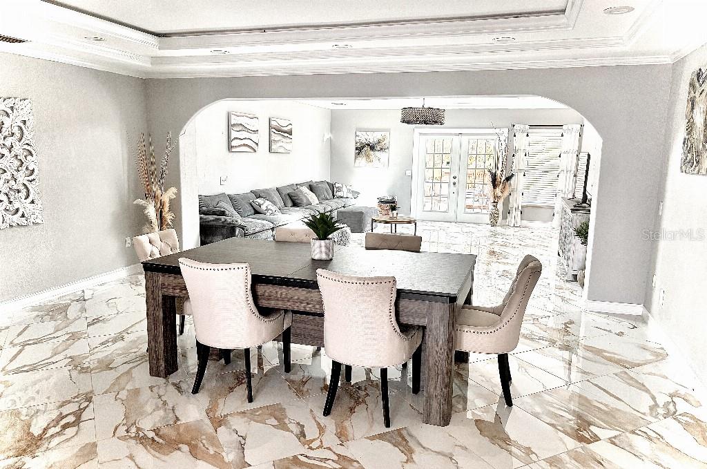 A dining area with a wooden table and upholstered chairs opens into a living room — 154 LOOKOUT POINT DRIVE, OSPREY, FL