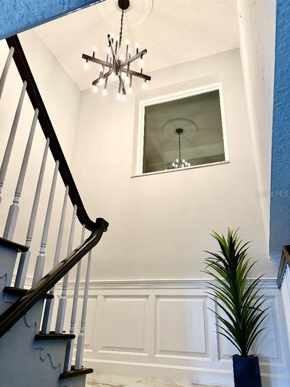 A staircase with a dark wood railing leads up past a wall with white wainscoting — 154 LOOKOUT POINT DRIVE, OSPREY, FL