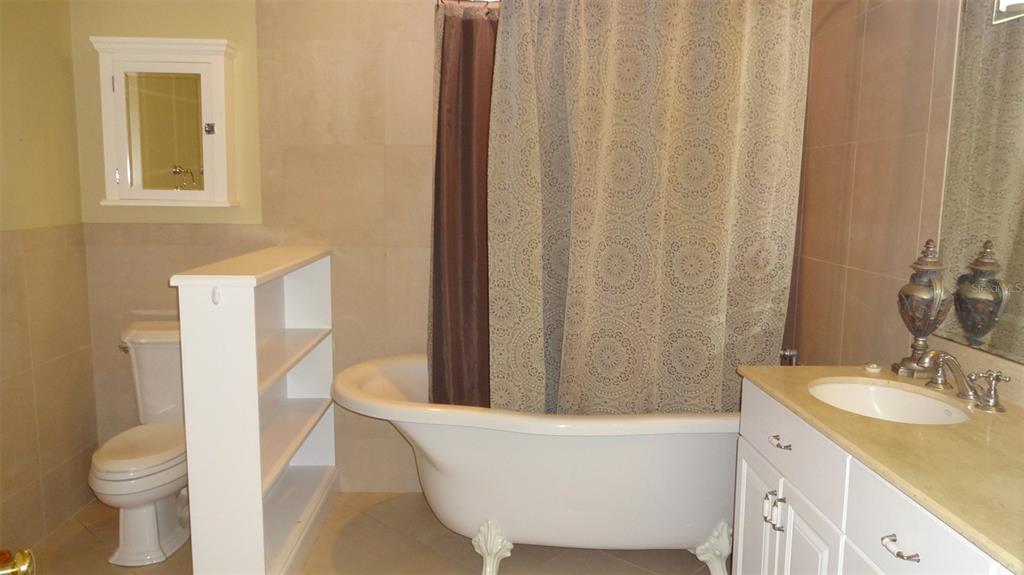 A bathroom features a clawfoot tub, a white vanity, a toilet, and a wall-mounted cabinet — 1144 DELANEY AVENUE UNIT 1144, ORLANDO, FL