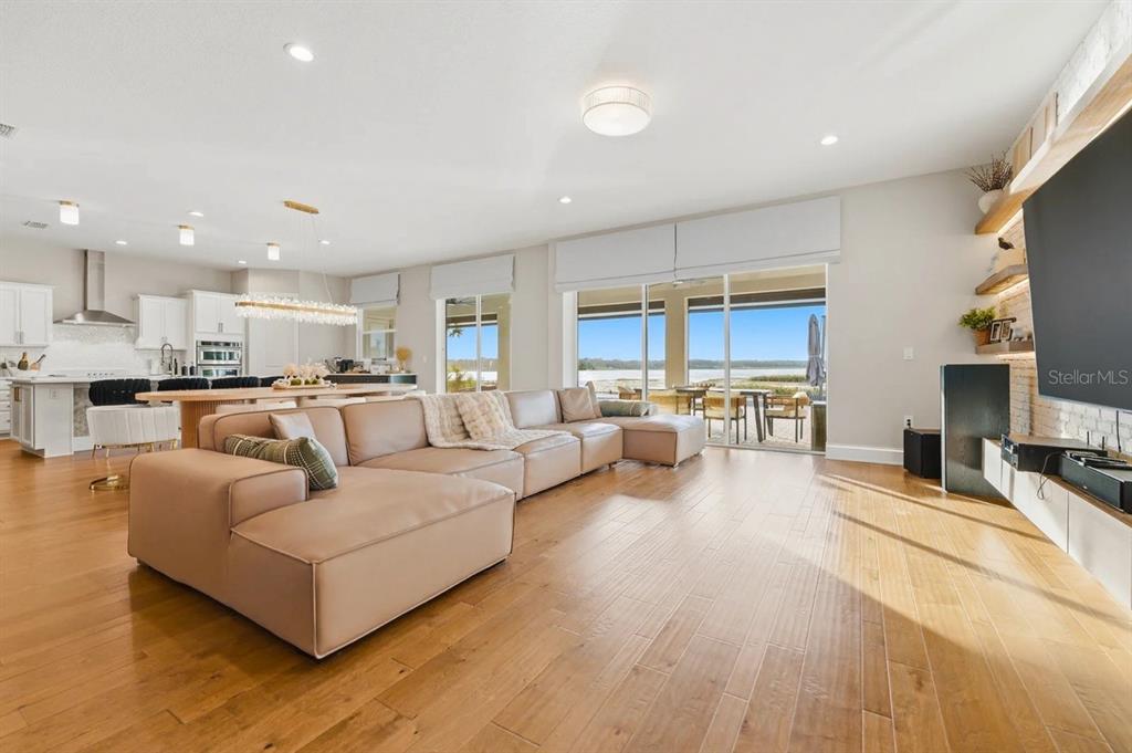 A swimming pool and spa overlook a lake at sunset with a paved patio area — 3387 BUOY CIRCLE, WINTER GARDEN, FL
