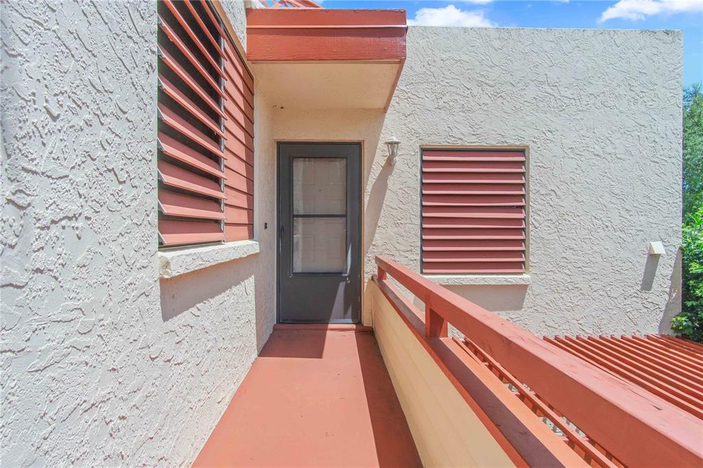 An exterior view of a balcony with a doorway, red railings, and louvered window shutters — 514 SPRING LAKES BOULEVARD, BRADENTON, FL