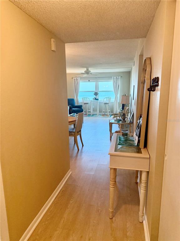 A hallway with light wood flooring leads to a living area with ocean views — 1270 GULF BOULEVARD UNIT 707, CLEARWATER BEACH, FL