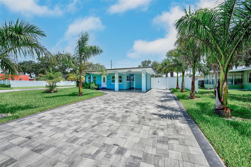 A turquoise house with a paved driveway and palm trees under a blue sky — 2425 BAYWOOD DRIVE E, DUNEDIN, FL