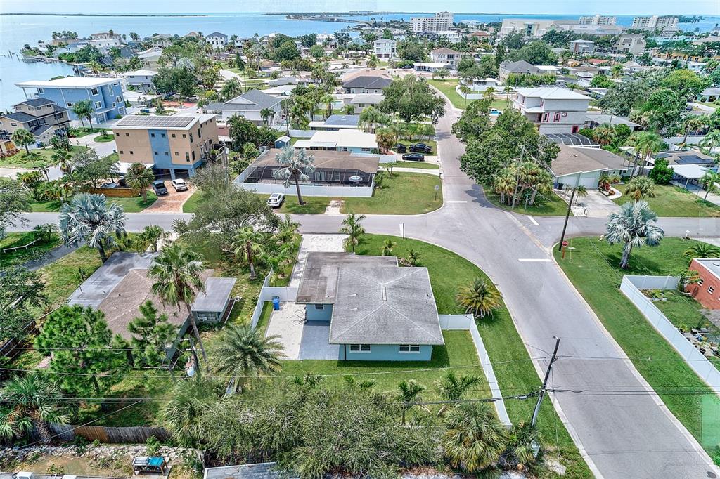 An aerial view shows a light blue house with a gray roof in a coastal neighborhood — 2425 BAYWOOD DRIVE E, DUNEDIN, FL