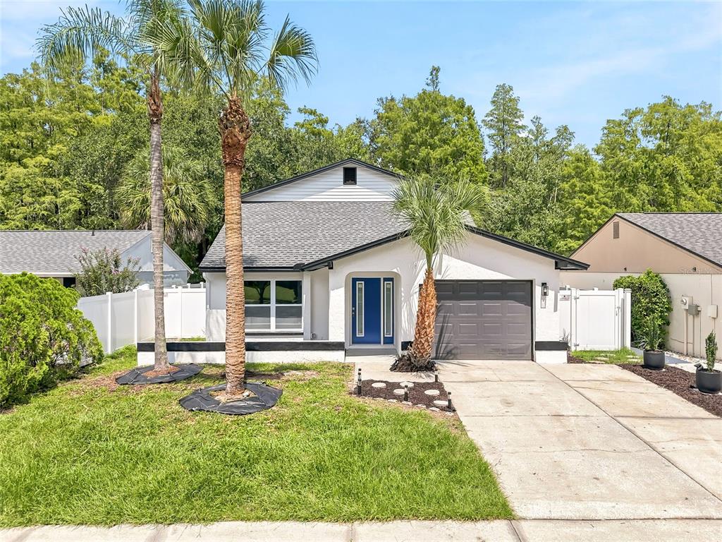 A single-story house with a white exterior, blue front door, and a gray garage door — 15924 WINDING DR, TAMPA, FL