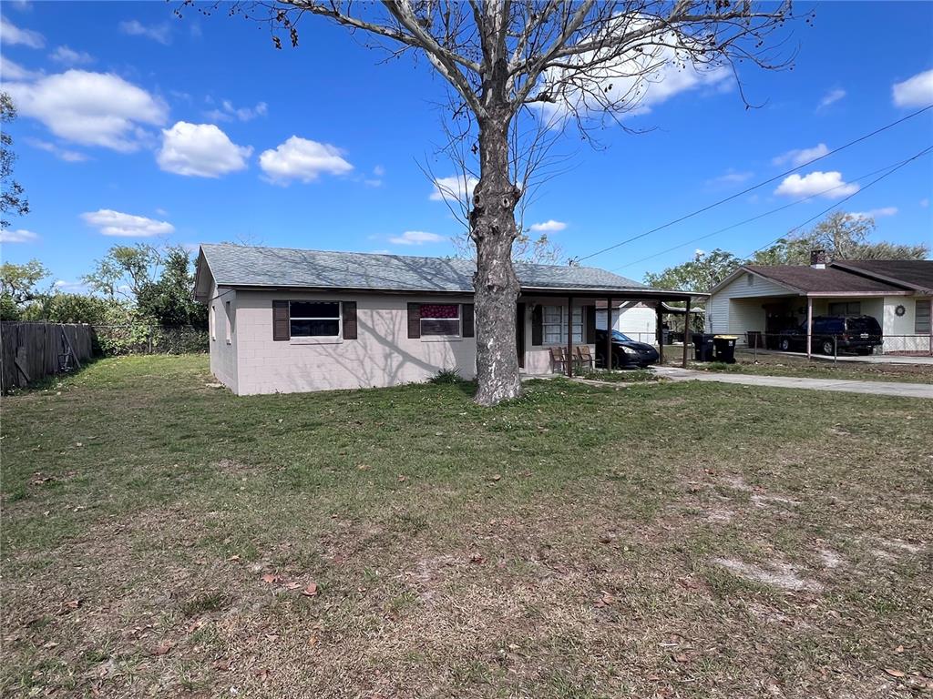 A single-story house with a large tree in the front yard and a carport — 589 DUNCAN CIRCLE E, AUBURNDALE, FL