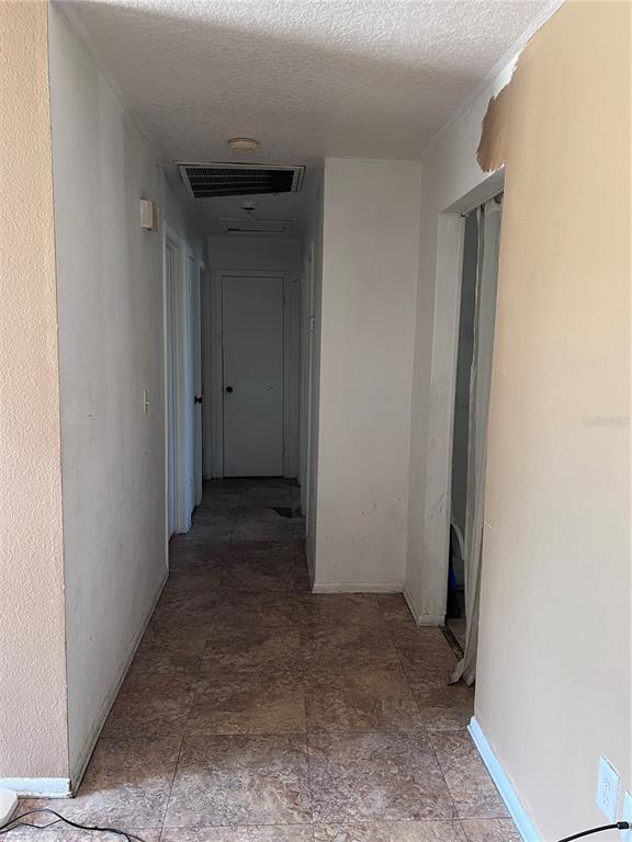 A narrow hallway with tiled flooring leads to a closed door at the end — 589 DUNCAN CIRCLE E, AUBURNDALE, FL