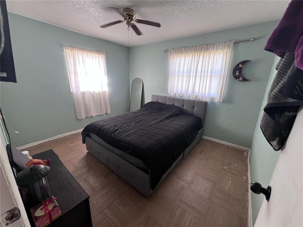 A bedroom with light blue walls, a gray tufted bed, and wood-look tile flooring — 589 DUNCAN CIRCLE E, AUBURNDALE, FL
