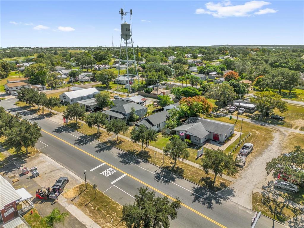 An aerial view shows a residential street with houses, trees, and a tall water tower — 312 E MAIN STREET, DUNDEE, FL