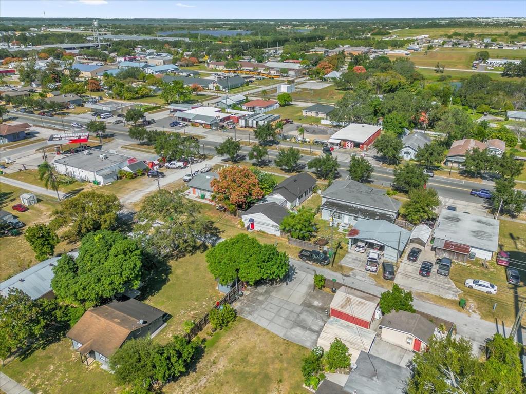 An aerial view shows a residential neighborhood with houses, driveways, and nearby commercial buildings — 312 E MAIN STREET, DUNDEE, FL