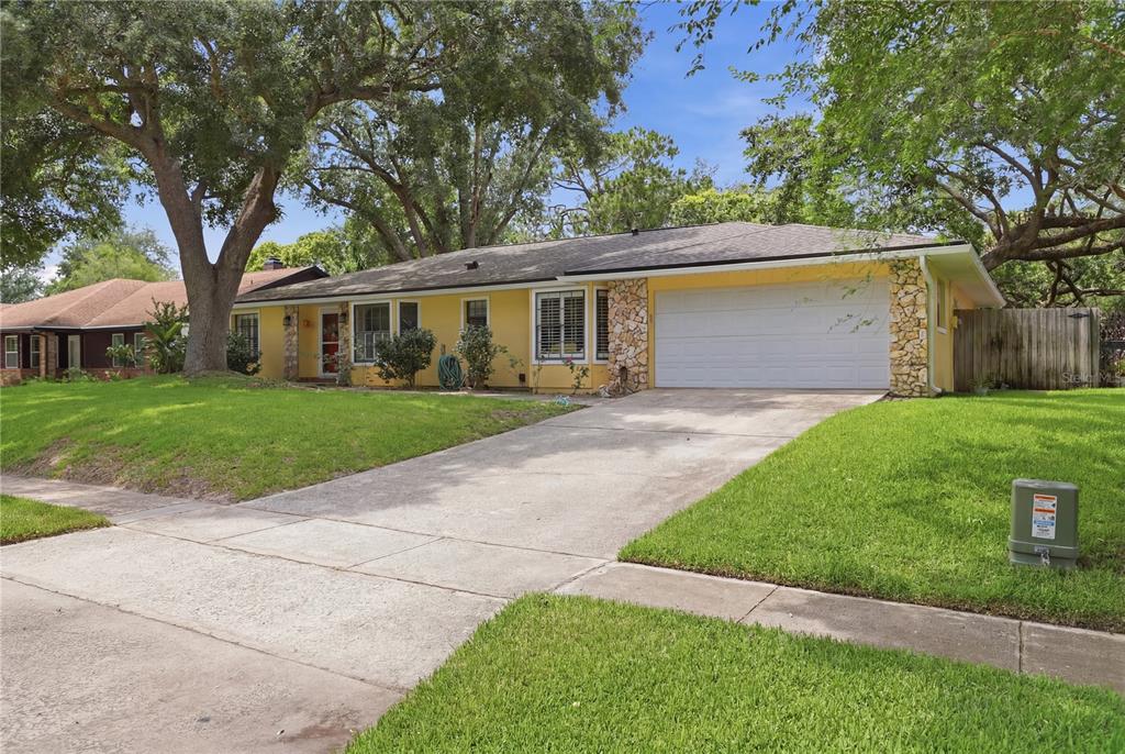 A yellow single-story house with a stone-accented facade and a two-car garage — 1701 WIND WILLOW ROAD, BELLE ISLE, FL