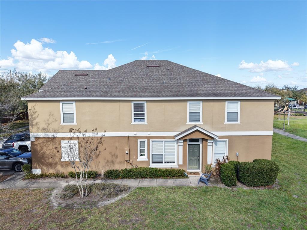 An exterior view of a two-story tan house with a dark shingled roof — 2018 ESTANCIA CIRCLE UNIT C, KISSIMMEE, FL