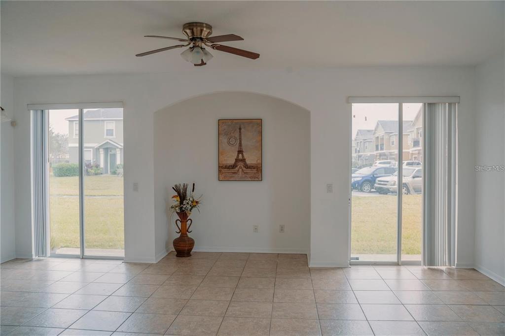 A room with tile flooring, a ceiling fan, and two sliding glass doors flanking an alcove — 2018 ESTANCIA CIRCLE UNIT C, KISSIMMEE, FL