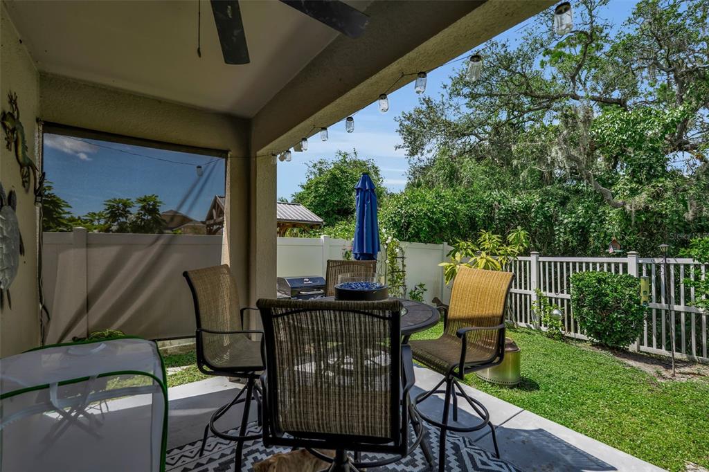 A covered patio features a dining set, string lights, and a view of the backyard — 5108 OLD TURNER LANE, PALMETTO, FL