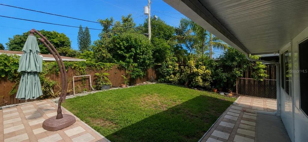 A backyard features a paved patio, a green lawn, and a wooden privacy fence — 2311 N 58TH AVENUE, HOLLYWOOD, FL